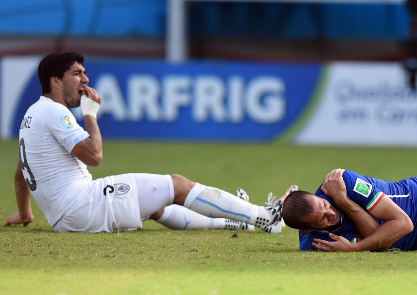 I due giocatori a terra. Chiellini si tiene la spalla dolorante, Suarez si lascia andare in una improbabile finta di dolore ai denti (Afp)
